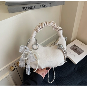 Detail of cream white handbag with pleated handle, silver chain and lace pearl pendant
