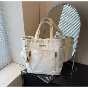 White canvas tote bag with front pocket and small coin purse in a lifestyle setting