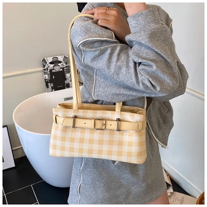 Detail of yellow gingham underarm bag showing adjustable buckle strap on model