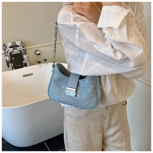 Blue denim underarm bag with silver rhinestones and chain strap in a lifestyle setting