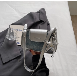Detail of silver metallic leather and blue denim patchwork bag with star charm