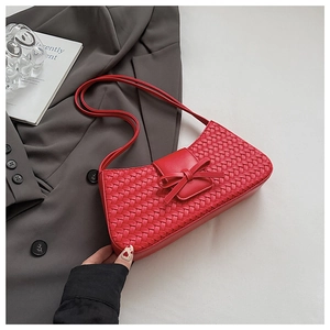 Close-up of red woven underarm bag with bow detail on a grey tailored suit jacket
