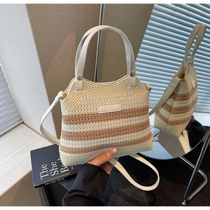Close-up of woven bucket bag featuring cream stripes and adjustable shoulder strap