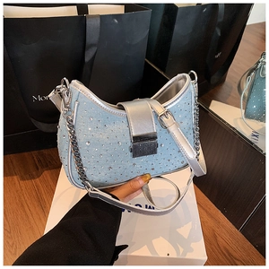 Detail of light blue denim crescent bag with shiny rhinestones and silver chain strap