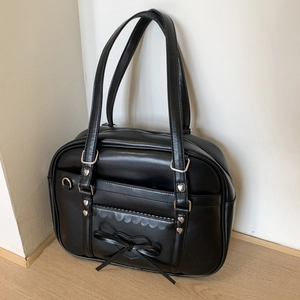 Detail of black glossy PU leather tote bag featuring a silk bow and heart metal rivets