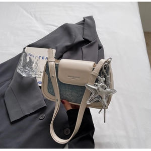 Close-up of patchwork shoulder bag with denim details and a silver starfish charm