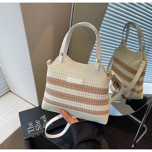 Close-up of woven bucket bag featuring cream stripes and leather SOLAR&MISS brand plate