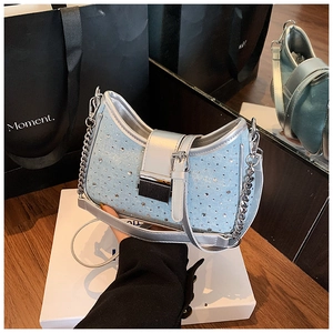 Close-up of light blue denim crescent bag with sparkling rhinestones and silver chain