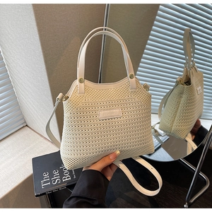 Detailed macro view of the cream-white woven texture and leather logo on the bucket bag