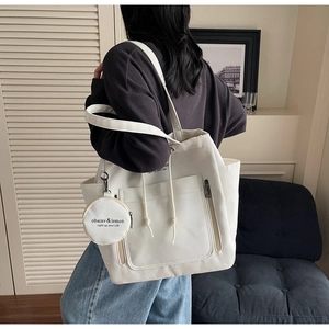 Detail view of large cream canvas tote bag with drawstring closure and small round pouch
