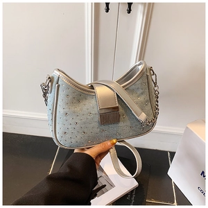 Detail of light blue denim shoulder bag featuring sparkling rhinestones and silver buckle