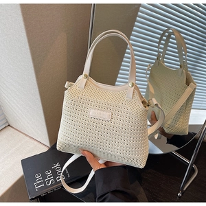 Close-up of beige woven bucket bag with leather handle and brand tag in mirror reflection