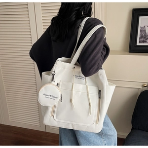 Detail of white canvas tote bag with side pockets and a small round hanging coin purse