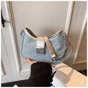 Detailed close-up of light blue denim crescent bag with sparkling rhinestones and chain