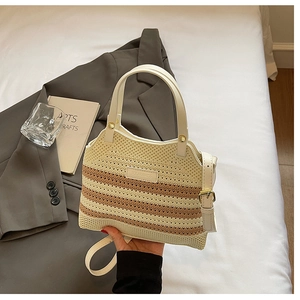 Detail of hand-woven bucket bag with cream knit texture and leather strap in soft setting