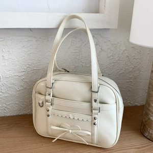Close-up of cream white PU leather bag with heart studs and a decorative bow detail