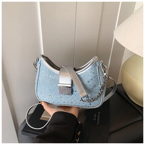 Detail of light blue denim underarm bag with sparkling rhinestones and silver metal hardware