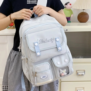 Gros plan du sac à dos bleu clair montrant le tissu durable et les boutons blancs décoratifs