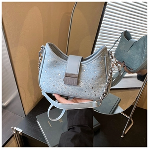 Detail of light blue denim crescent bag with shiny rhinestones and silver chain strap