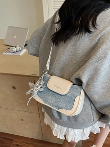 Blue denim and off-white leather shoulder bag with star charm in a lifestyle scene