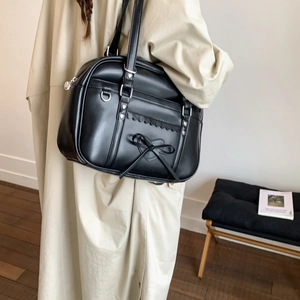 Black matte leather tote bag with bow detail and heart embossing in a lifestyle setting
