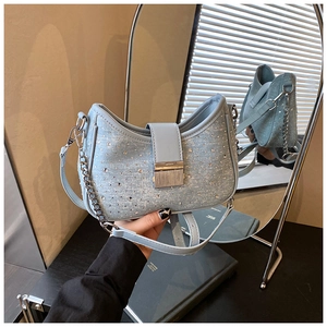 Detail of light blue denim shoulder bag with sparkling rhinestones and silver chain strap