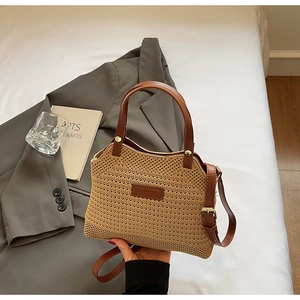 Detail of woven straw handbag featuring brown PU leather trim and adjustable long shoulder strap