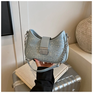 Close-up of light blue denim crescent bag with sparkling rhinestones and chain strap detail