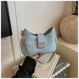 Detailed macro view of light blue denim underarm bag with silver rhinestones and chain strap