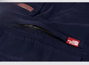Gros plan d'une poche zippée en métal sur un pantalon cargo bleu foncé avec étiquette