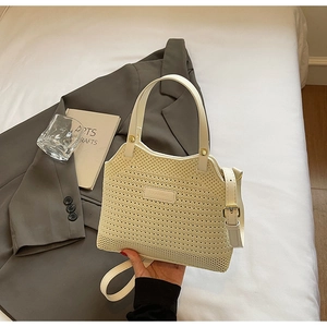 Detail of cream woven handbag with leather handles and adjustable shoulder strap texture