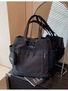 Black canvas tote bag with drawstring, front zipper pocket and round charm for women