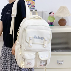 Vue détaillée du sac à dos en toile crème avec design multi-poches et breloque peluche