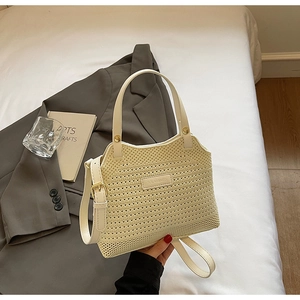 Detailed knit texture of a cream-colored woven bucket bag with a metal brand logo plate