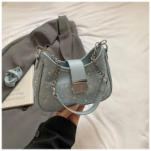 Detail of light blue denim crescent bag with silver rivets and metallic chain strap