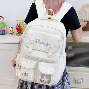 Vue détaillée d'un sac à dos blanc en toile avec poches fonctionnelles et broderies
