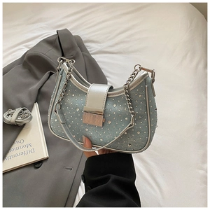 Detail of light blue denim crescent bag with sparkling rhinestones and silver chain