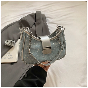 Detail of light blue denim underarm bag with silver rhinestones and chain strap