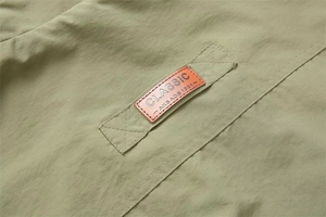 Macro detail of casual vest with orange leather classic patch and green synthetic fabric