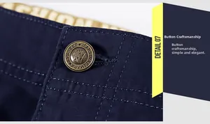 Gros plan du bouton en métal bronze gravé et des coutures sur le pantalon cargo homme