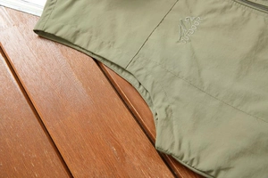 Detailed macro view of olive green outdoor vest chest with mountain embroidery and text