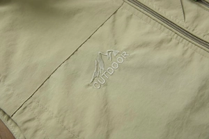 Detailed macro view of outdoor vest featuring mountain embroidery and windproof fabric
