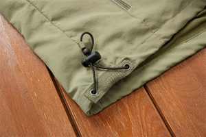 Detail of olive green outdoor vest hem with adjustable elastic drawstring and metal eyelet