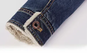 Détail du poignet d'une veste en jean bleu foncé avec doublure en polaire et bouton métal