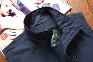 Detail of navy casual vest collar showing green woven size label on dark wood table
