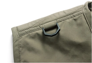 Close-up of military green tactical vest shoulder with reinforced seams and black D-ring hook