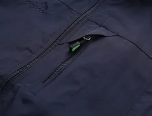 Détail du gilet outdoor avec poche zippée en métal et broderie logo montagne