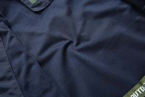 Macro detail of breathable dark blue mesh lining and outdoor branding on the casual vest