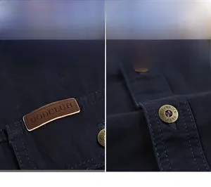 Detail of navy blue twill shirt with brown leather label and vintage bronze metal button