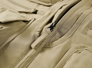Détail du gilet extérieur kaki montrant la fermeture éclair et les doubles coutures